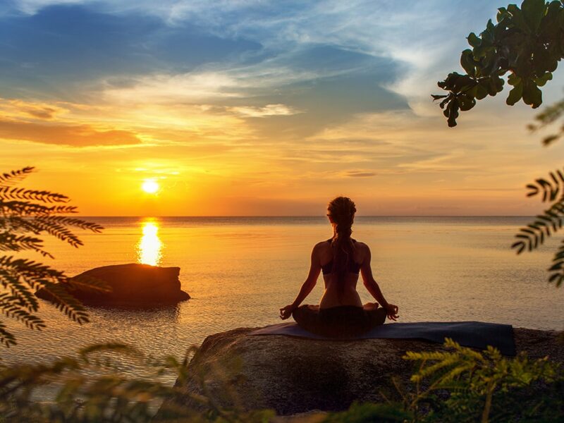 a girl doing yoga in the sunset at a wellness retreat in Greece