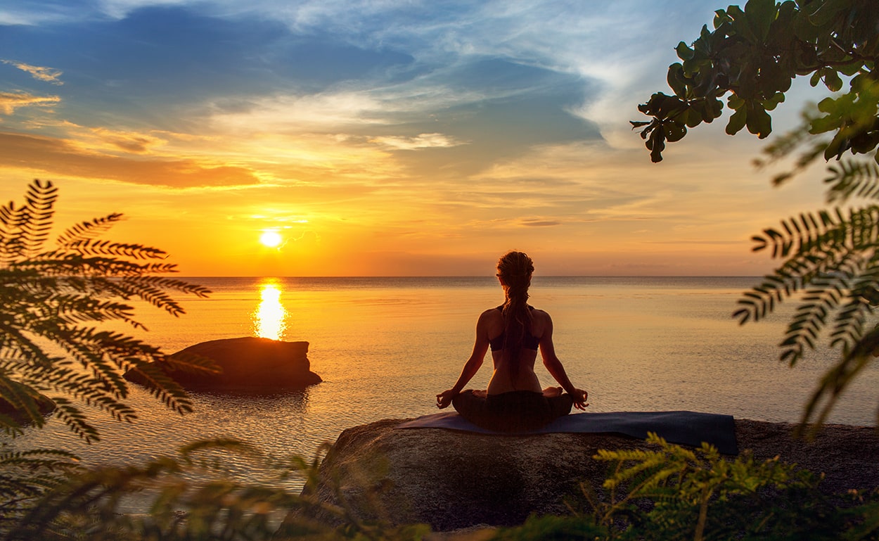 a girl doing yoga in the sunset at a wellness retreat in Greece