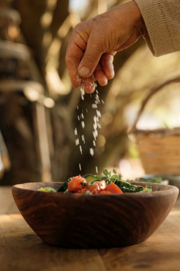 Man pouring salt on a greek salad